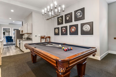 A pool table with a brown leather cover and a white cue ball is in the center of the room.