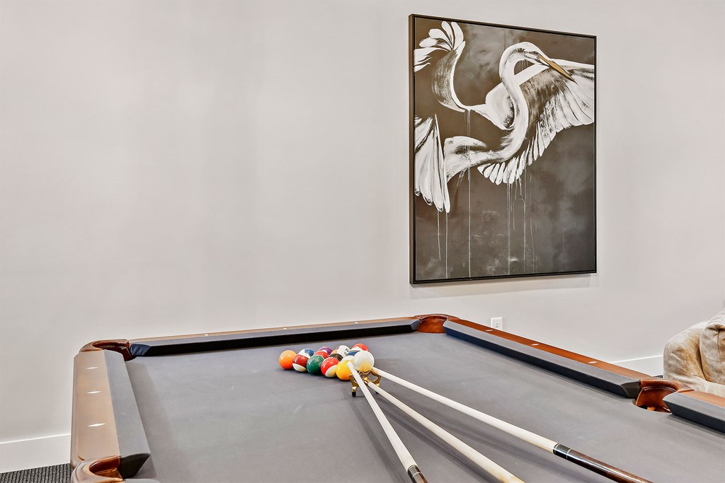 A pool table with a painting of a bird above it.