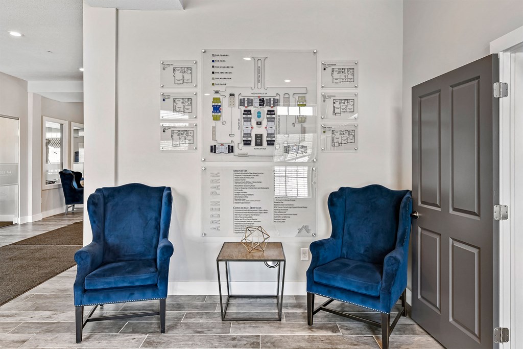 Two blue chairs are in front of a wall with diagrams and plans.