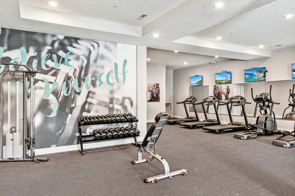 A gym with a variety of equipment including treadmills, weights, and exercise machines.
