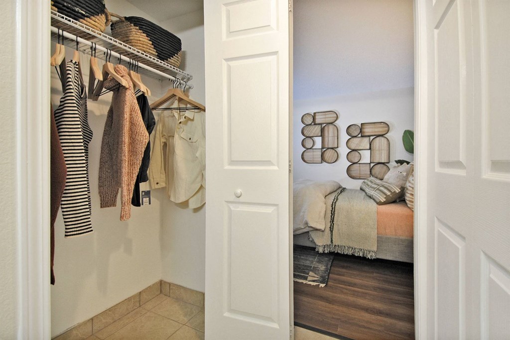an open closet with clothes hanging on a rack in a bedroom