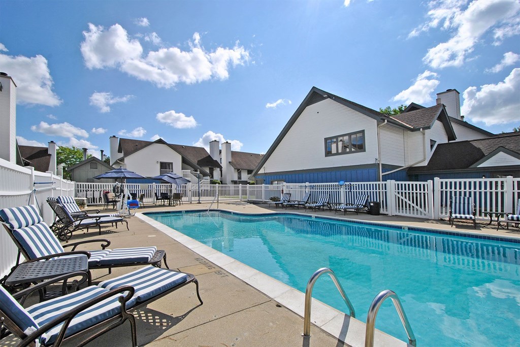 resort style swimming pool is next to building and lounge chairs