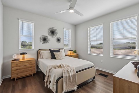 A bedroom with a bed, nightstands, and a ceiling fan.
