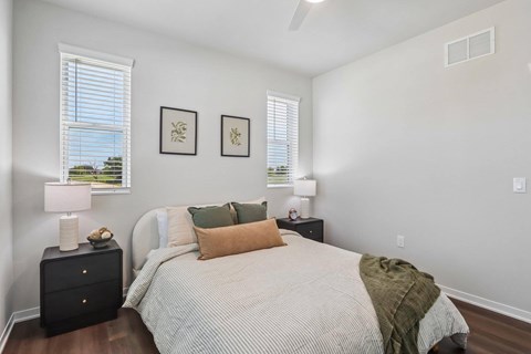A bedroom with a bed, nightstands, and pictures on the wall.