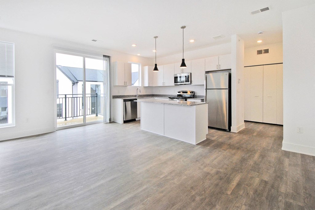 a white kitchen with a large island and a stainless steel refrigerator