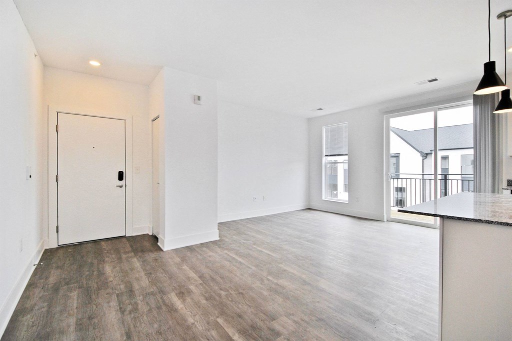 the living room and kitchen of a new home with white walls and wood flooring