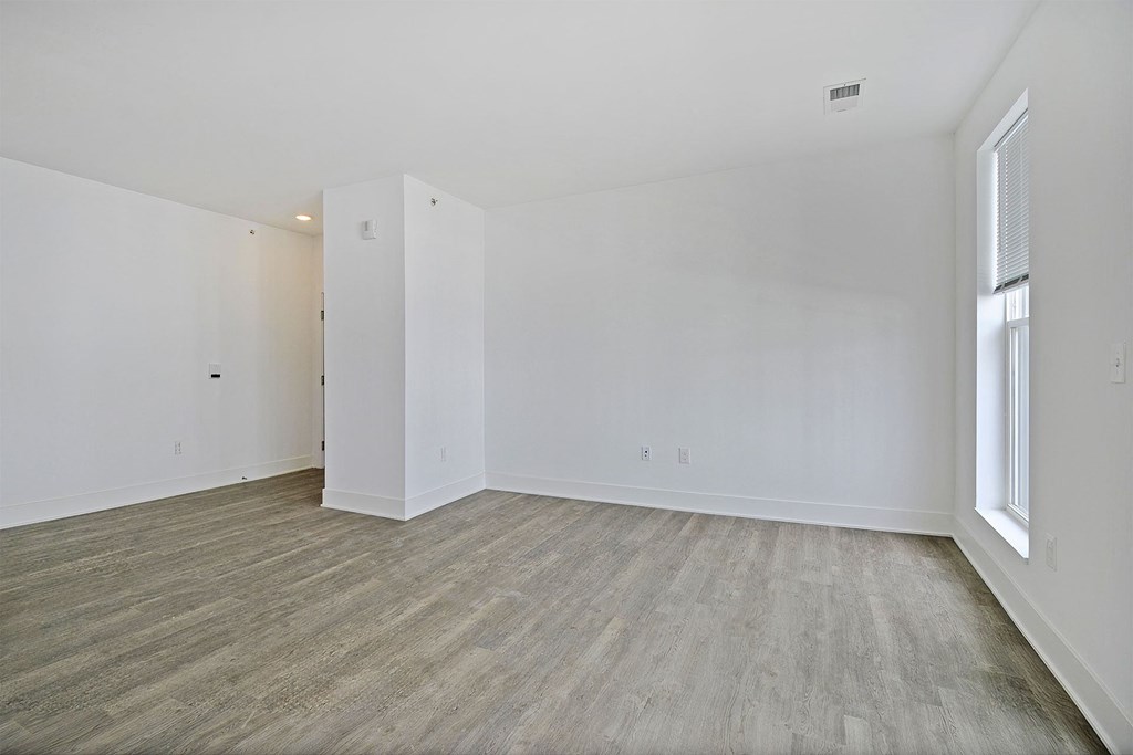 a bedroom with white walls and wood flooring and a window