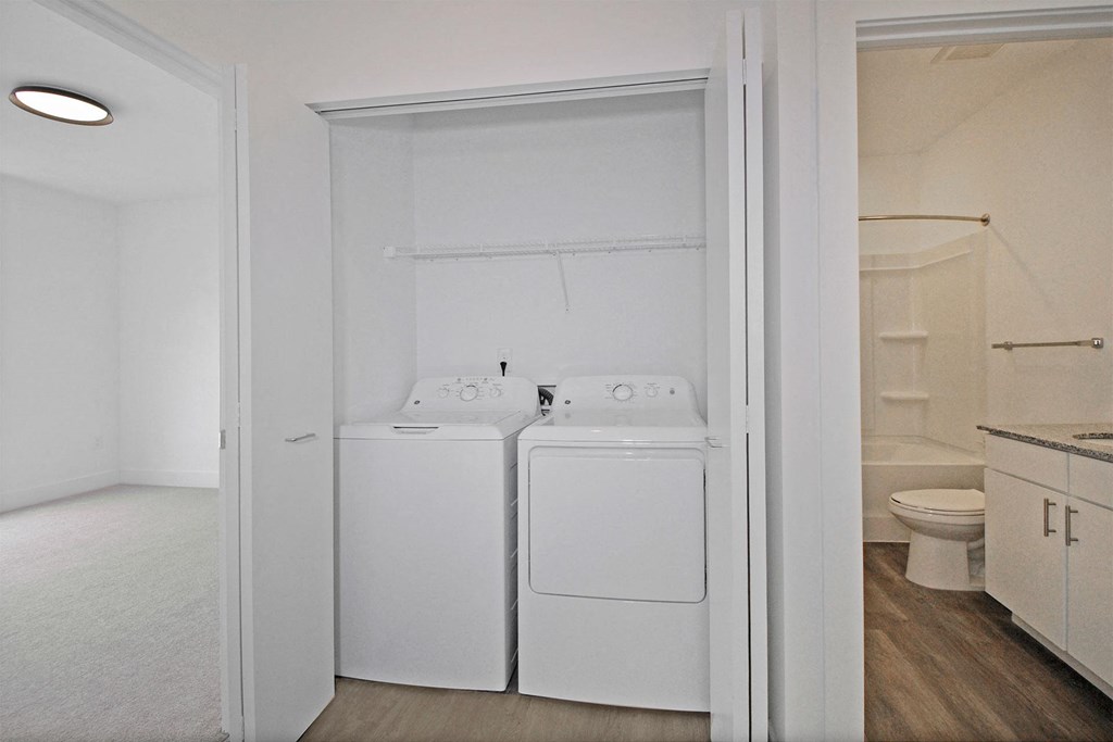 a white washer and dryer in a room with a sink and a toilet