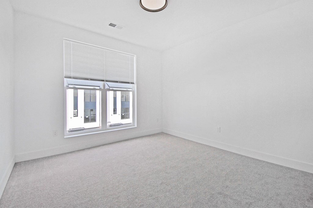 an empty living room with a window and white walls