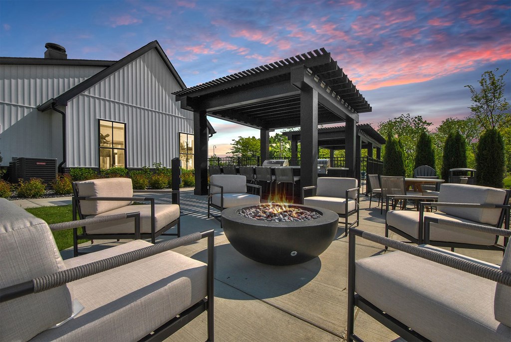 A patio with a fire pit and chairs.