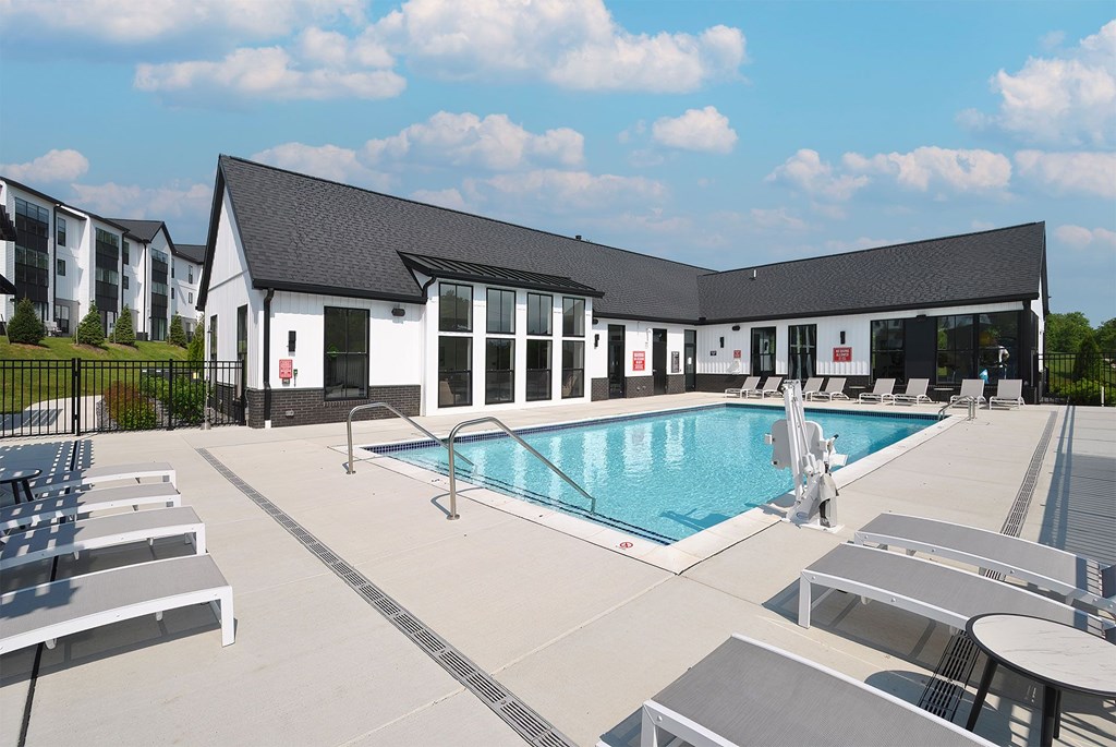 A large outdoor swimming pool with sun loungers and a building in the background.
