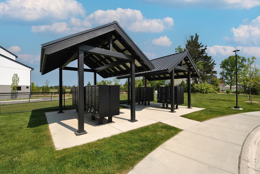 A black pavilion with a metal roof is situated in a grassy area.