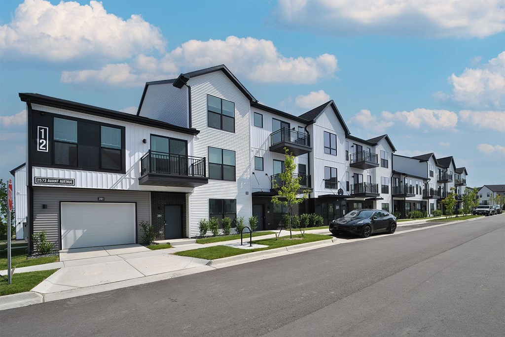 A row of modern townhouses with a car parked on the street.