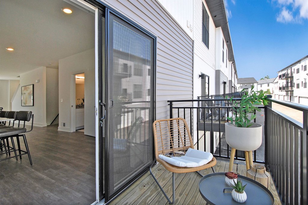 a balcony with a chair and a table and a sliding glass door