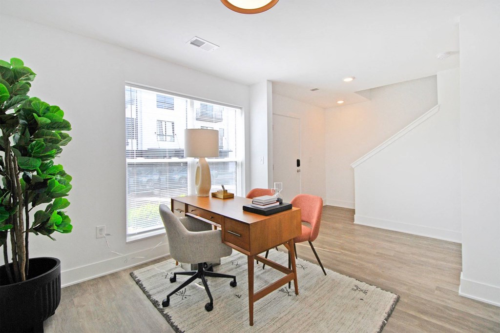 a home office with a large window and a desk with two chairs