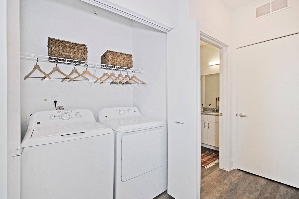 a white washer and dryer in a room with a door to a bathroom