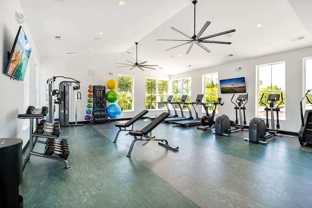 the gym has plenty of exercise equipment and windows