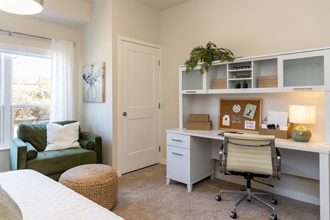 A white desk with a chair and a bulletin board on it.