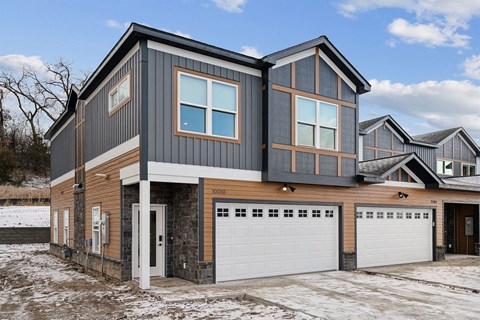A modern house with a grey and brown exterior and a white garage door.