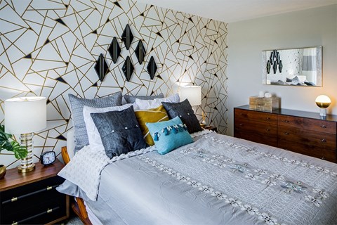 a bedroom with a bed and a geometric wallpaper