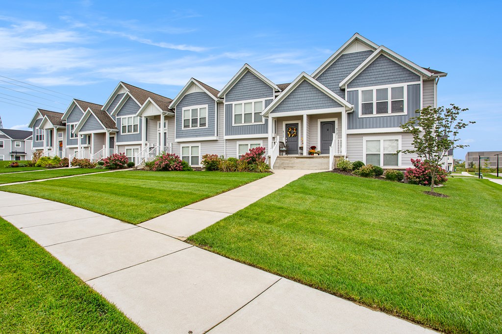 A row of houses with a sidewalk in front.