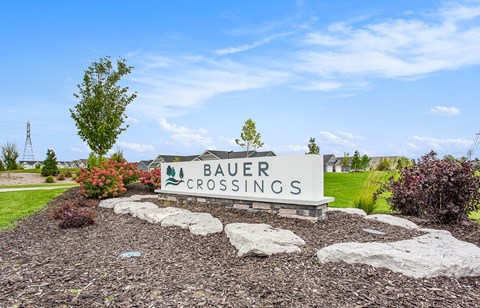 A sign that says Bauer Crossings is in front of a grassy area.