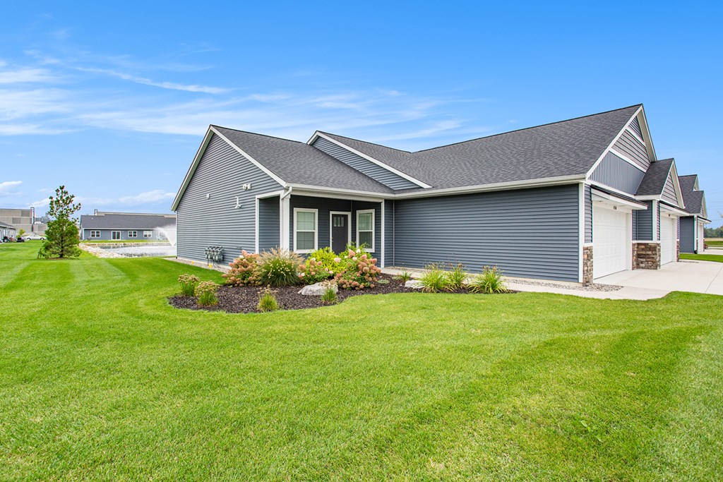 A grey house with a green lawn in front.
