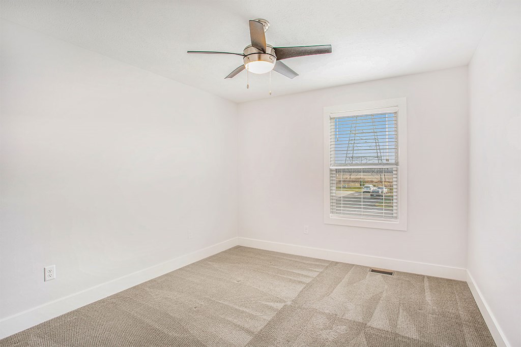 A room with a ceiling fan and a window with blinds.