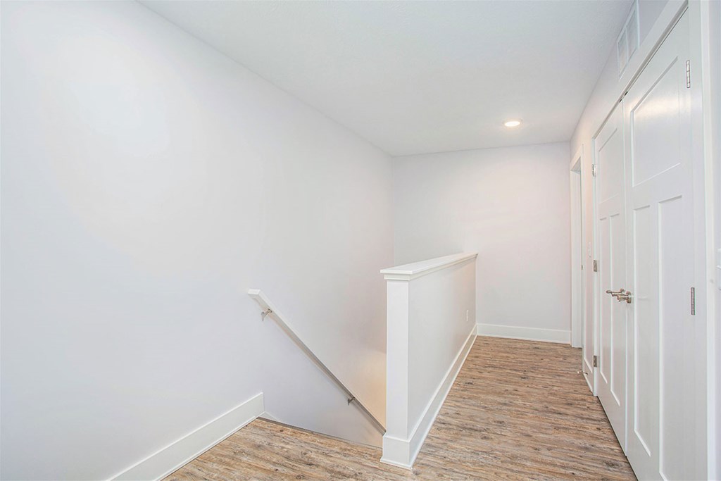 A white room with a wooden floor and a white door.
