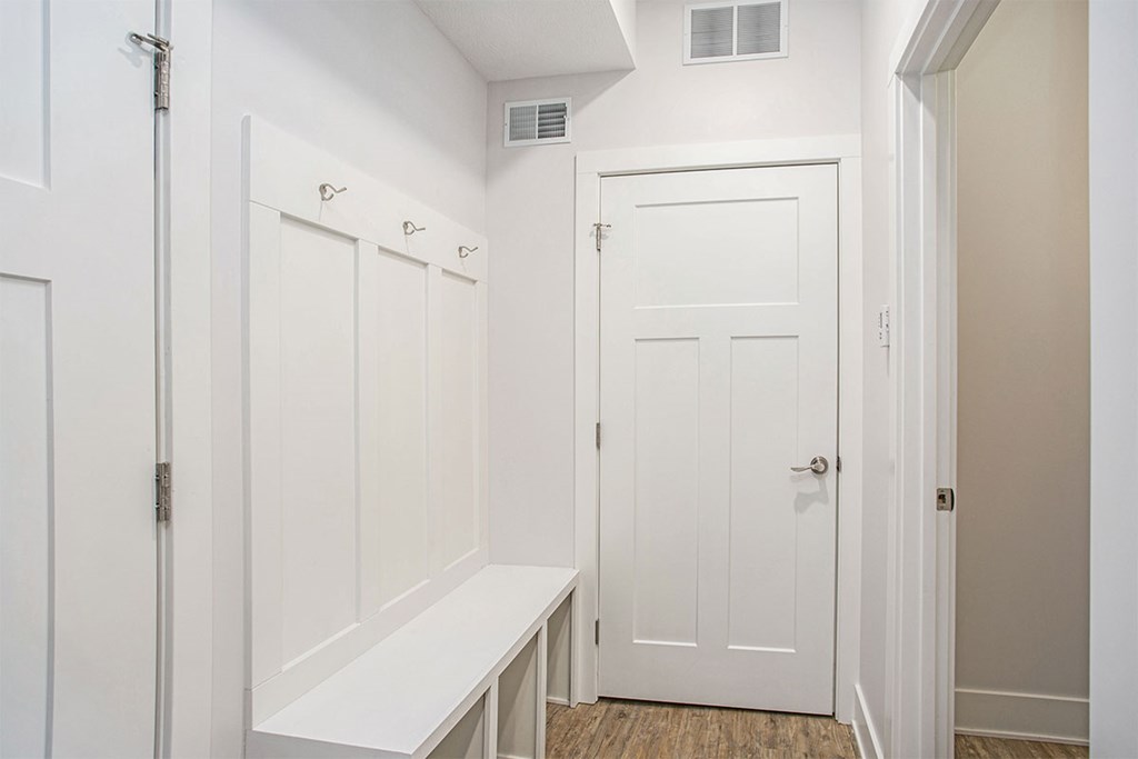 A white bathroom with a bench and a door.