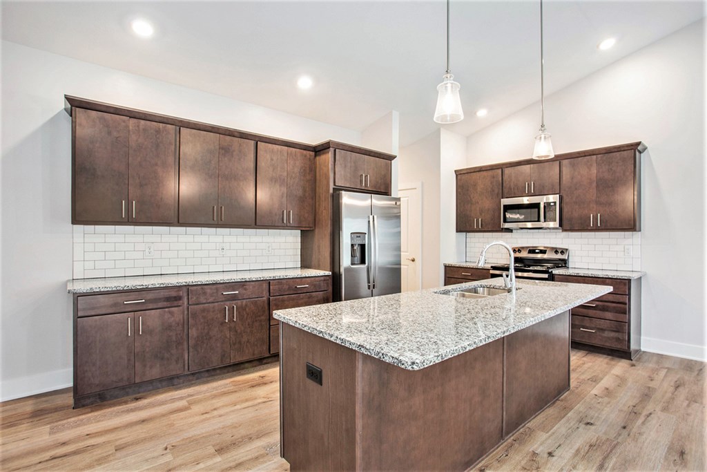 A kitchen with a granite countertop and wooden cabinets.