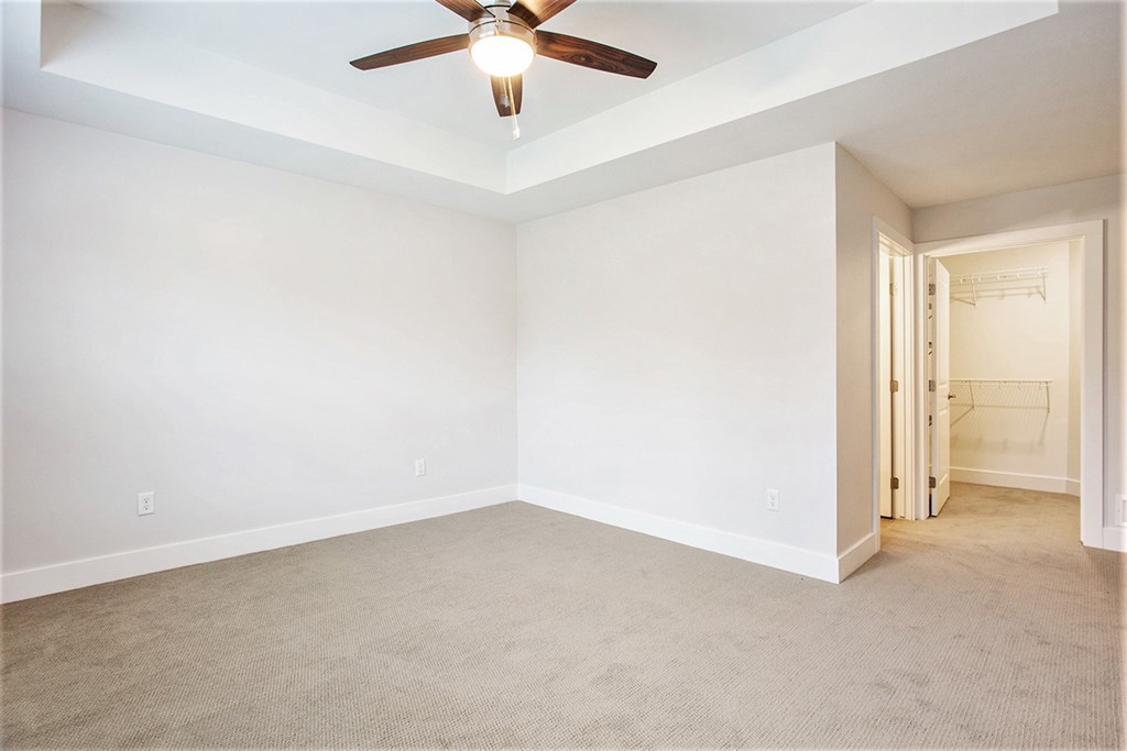 A room with a ceiling fan and carpeted floor.