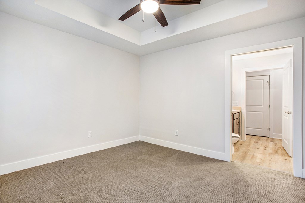 A room with a ceiling fan and carpeted floor.