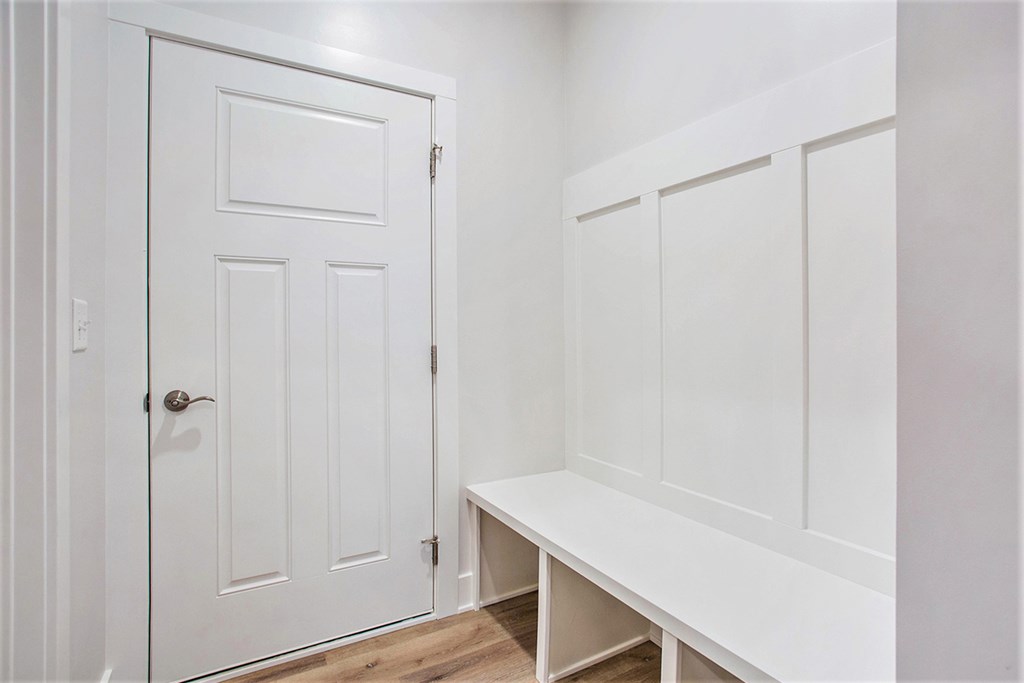 A white door with a white bench to the right of it.