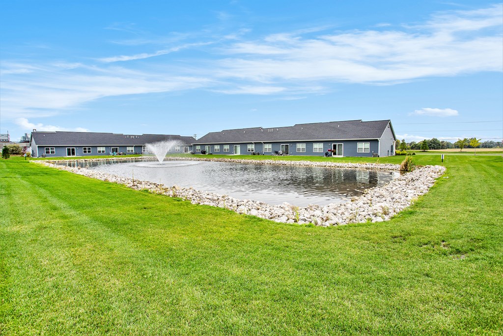 A building with a grey roof is surrounded by a grassy field.