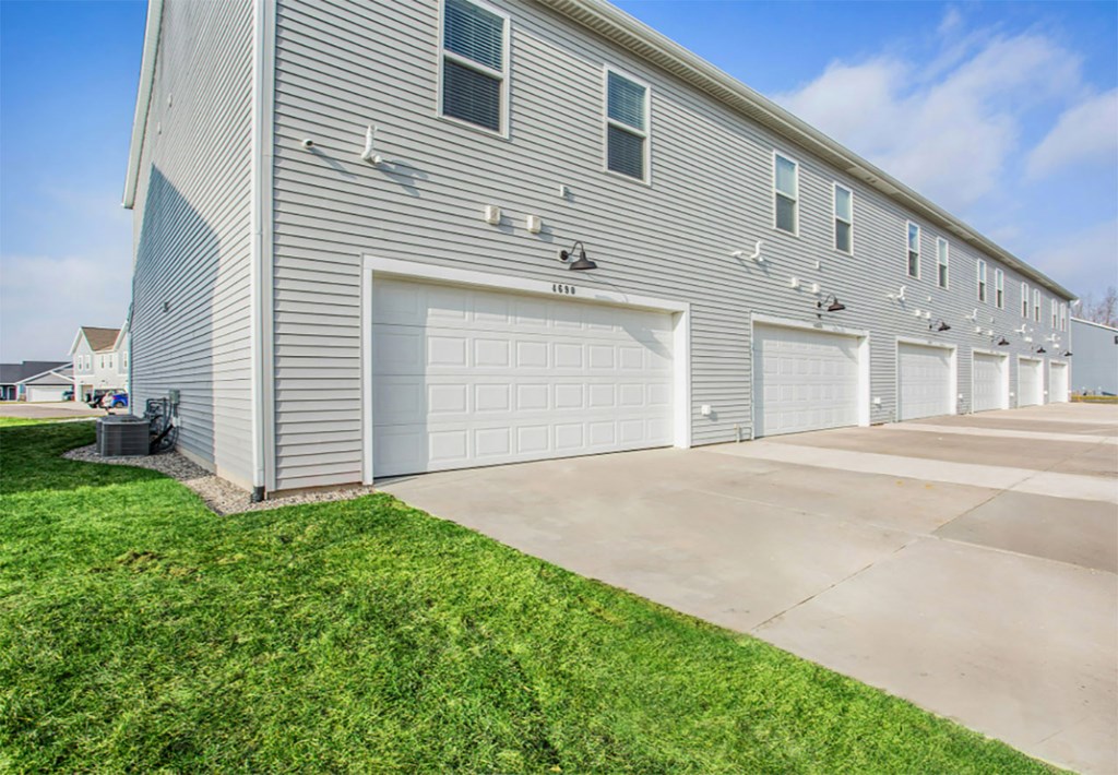 A long building with a grey facade and white garage doors.