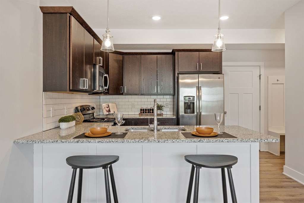 A modern kitchen with a white countertop and dark brown cabinets.