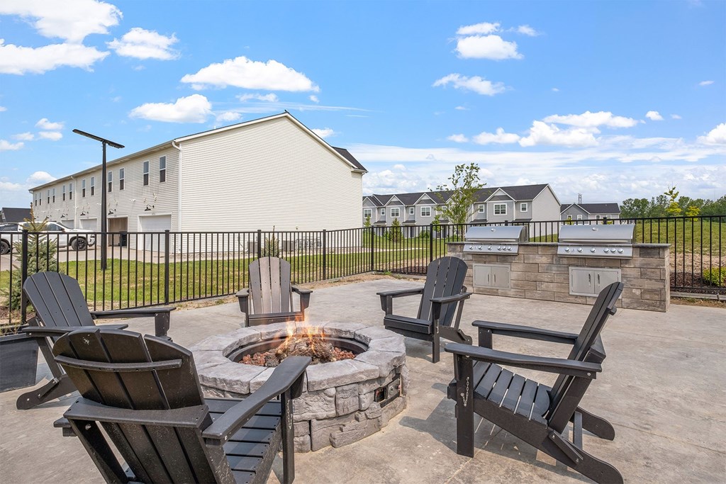 A fire pit is surrounded by four chairs on a patio.