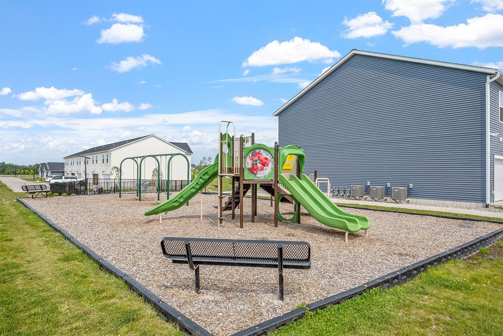 A playground with a green slide and a red flower on it.