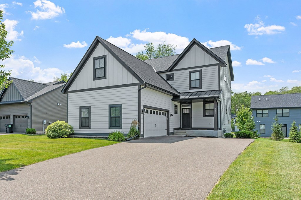 A large house with a grey roof and a driveway in front.