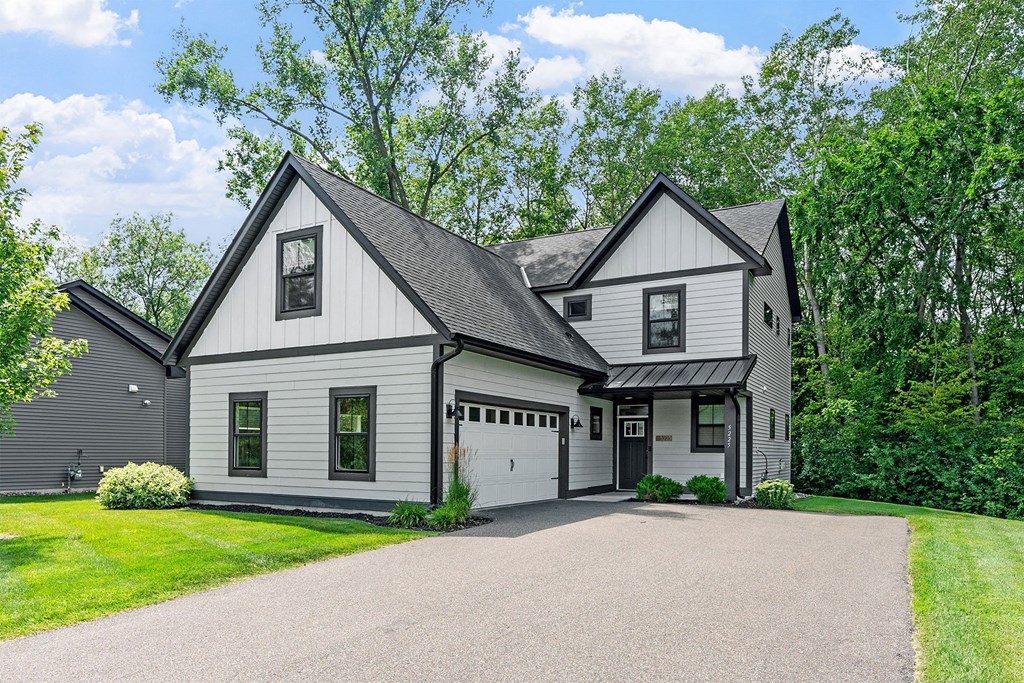 A white house with a black roof and a garage door.