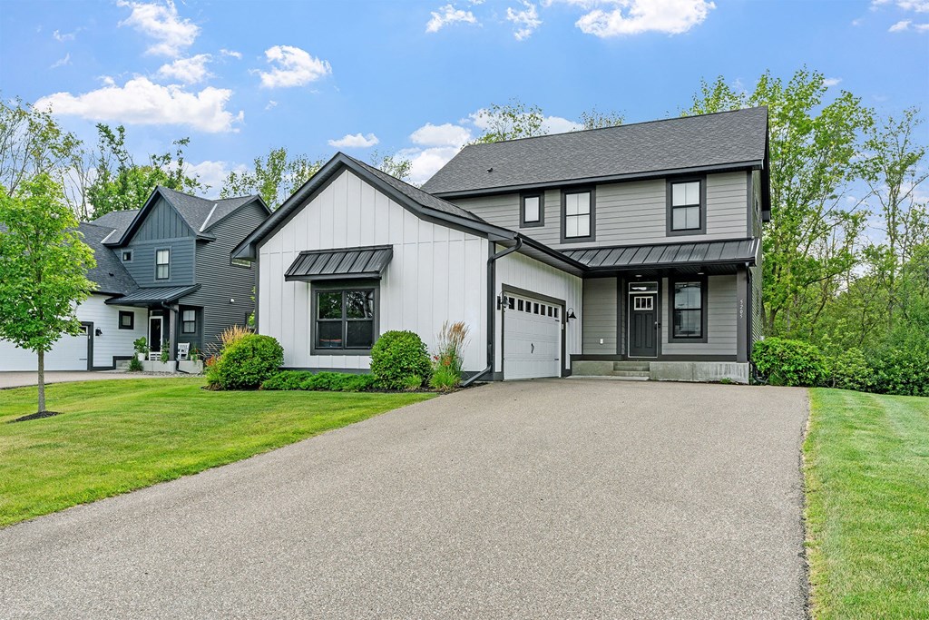 A house with a grey garage door and a black roof.