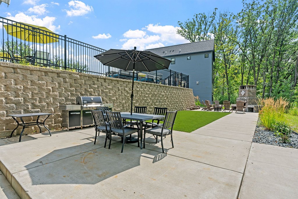 A patio with a table and chairs under an umbrella.
