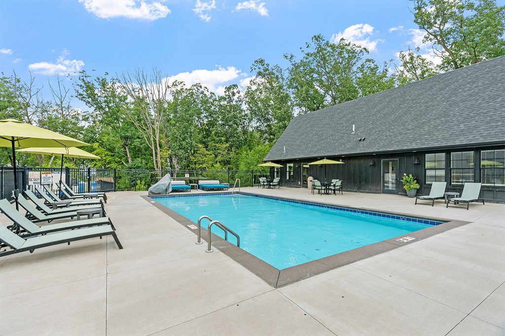 A pool with sun loungers and a building in the background.