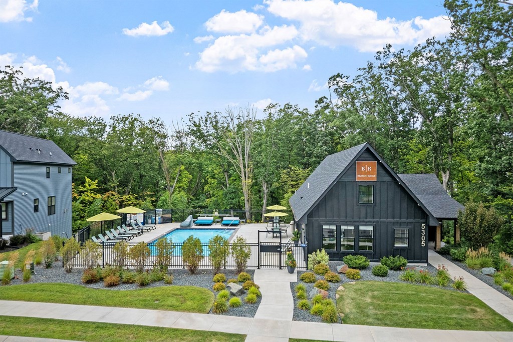 A black house with a pool in front of it.