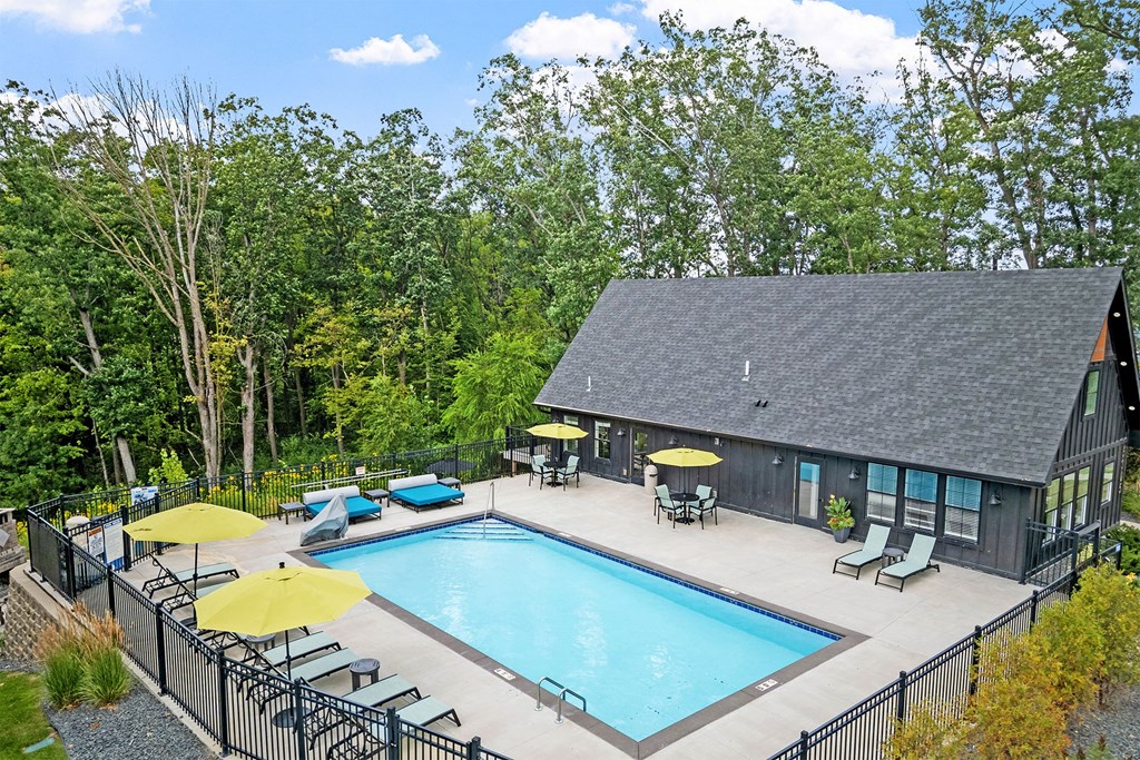 A pool with a yellow umbrella and a black fence.