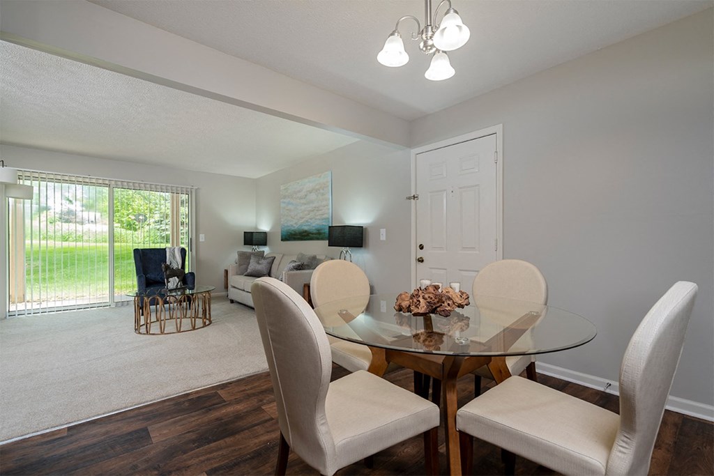 an open living room and dining room with a glass table and chairs