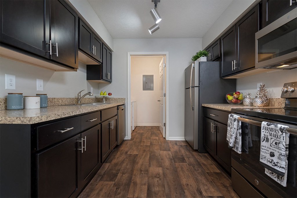 a kitchen with dark cabinets and a stainless steel refrigerator