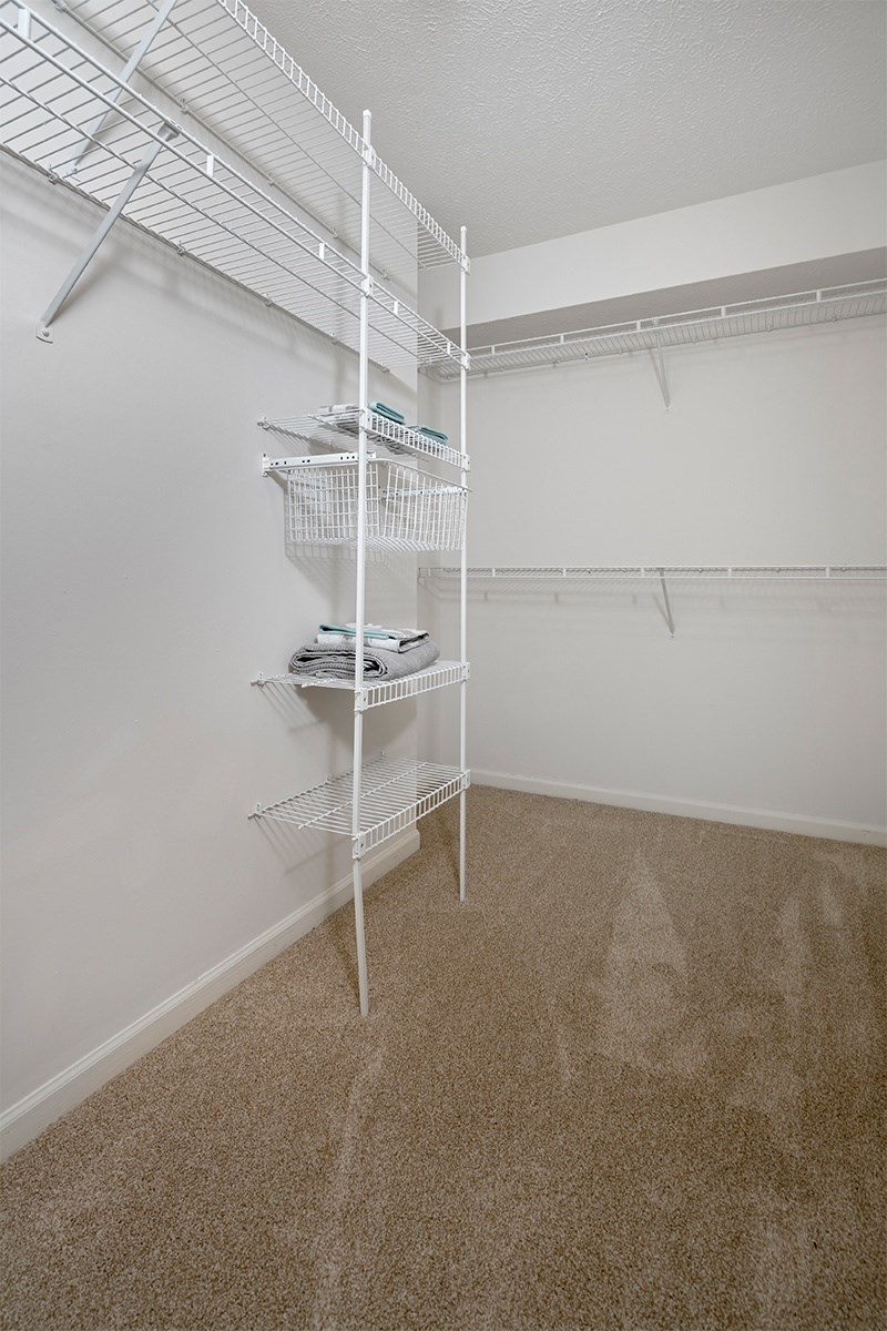a spacious closet with white walls and a white shelving unit