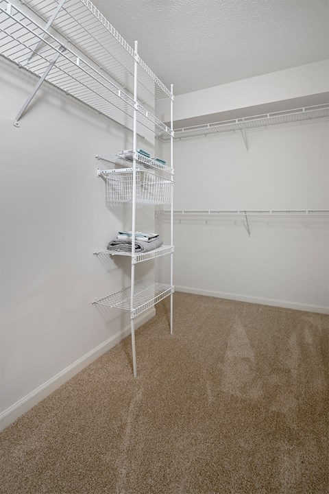 a spacious closet with white walls and a white shelving unit